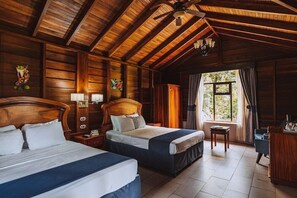 A wooden cabin-style room with two beds, a ceiling fan, and a window with curtains. - Campo Verde (La Fortuna)
