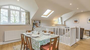 A dining area with a table set for four, a white railing, and a view of trees outside.