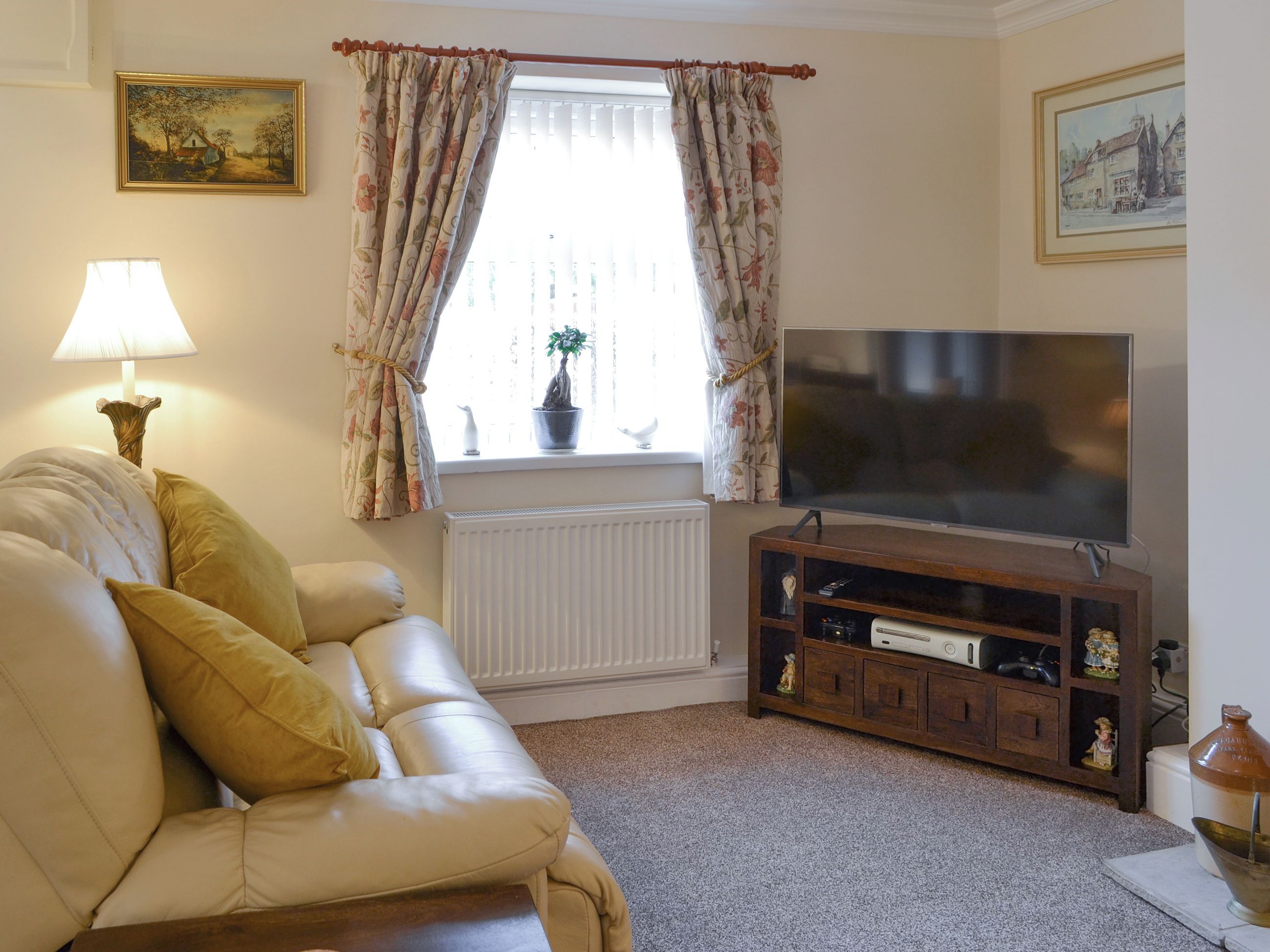 A living room with a sofa, TV, radiator, and decorative items.