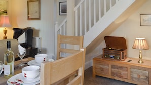 A dining area with a wooden chair, a table set with white plates and cups, a radio on a wooden side table, and a staircase. - 2 bedroom accommodation in North Cave (North Cave)