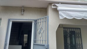 A two-story building with a balcony, a gated entrance, and a window with a metal grille.