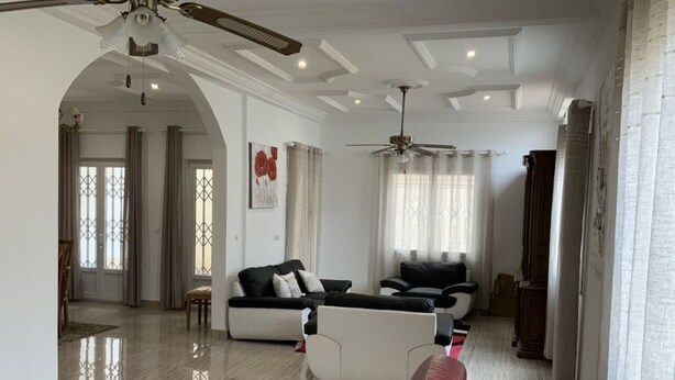 A spacious living room with a large sofa set, a red accent sofa, and a wooden coffee table.