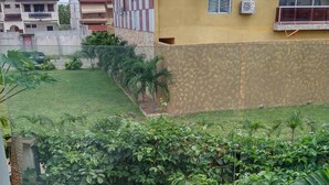 A residential area with a yellow house, a green lawn, and a concrete wall.