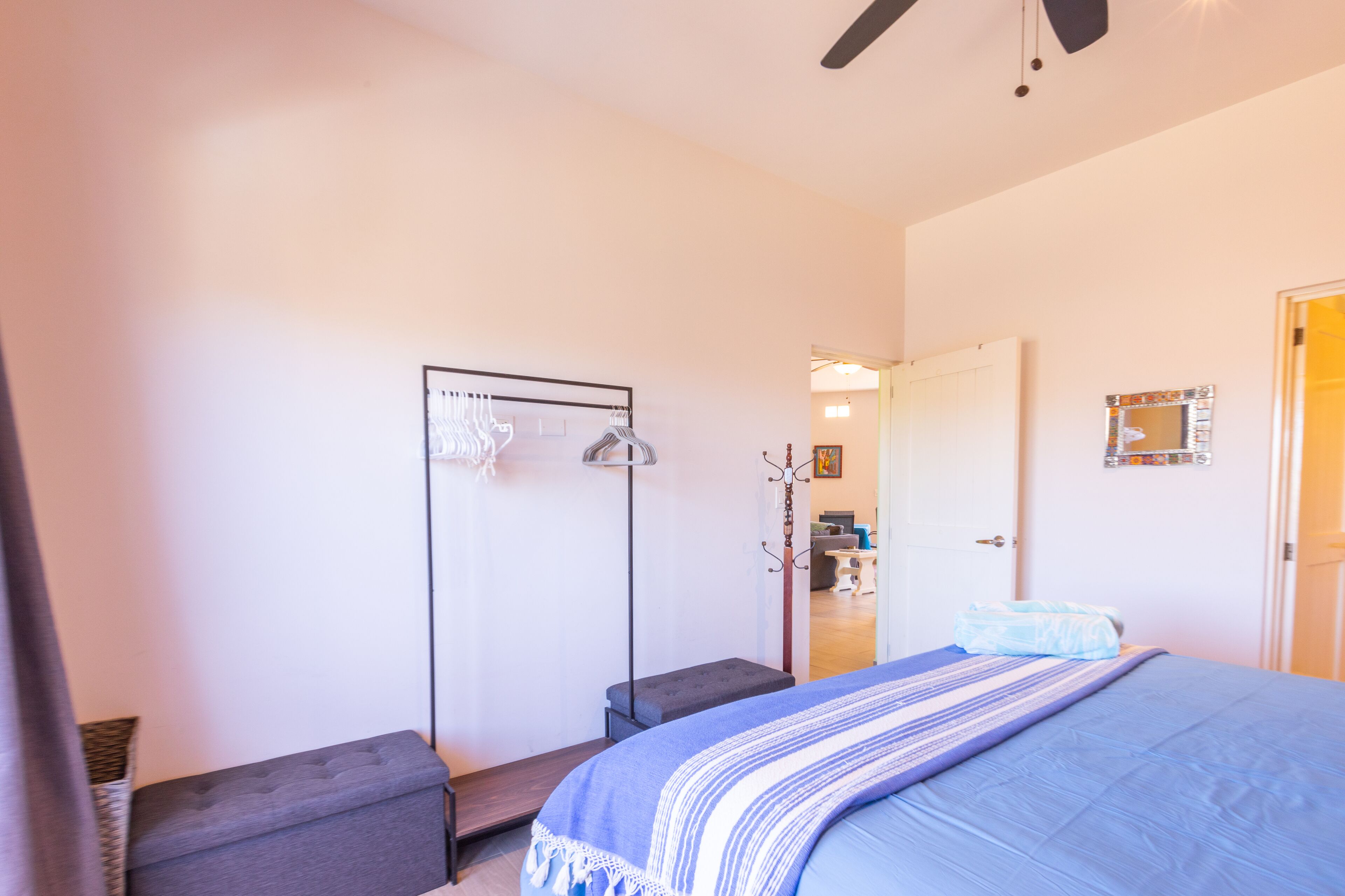 Une chambre à coucher comprenant un lit, un banc, une armoire et une porte donnant sur une autre pièce.