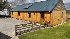 Il s’agit d’un bâtiment en bois, de style grange, doté d’un toit en pente, d’une allée gravillonnée et d’une clôture en bois.