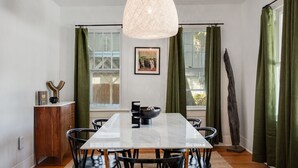 Een eethoek met een marmeren tafel, zwarte stoelen, een houten kast en een hanglamp.