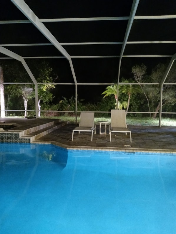 A pool area with lounge chairs and a covered patio.