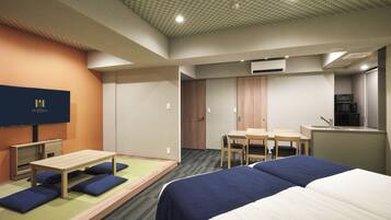 Habitación de hotel con cama, escritorio, silla, televisión y kitchenette.