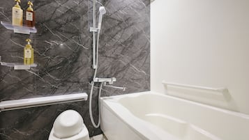 A bathroom with a bathtub, a shower, and a toilet. There are shelves with toiletries on the wall.