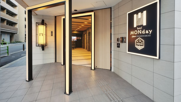 A hotel entrance with a modern design, a visible staircase, and a sign advertising a Monday special offer. - MONday Apart Premium GINZA SHINTOMICHO (Tokyo)