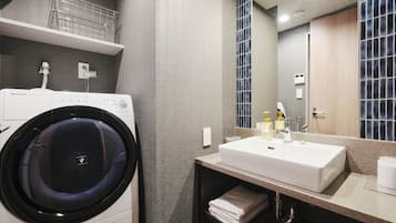 A modern bathroom with a built-in washing machine, a sink, and a mirror.