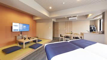 A hotel room with a bed, a desk, a television, and a kitchenette.