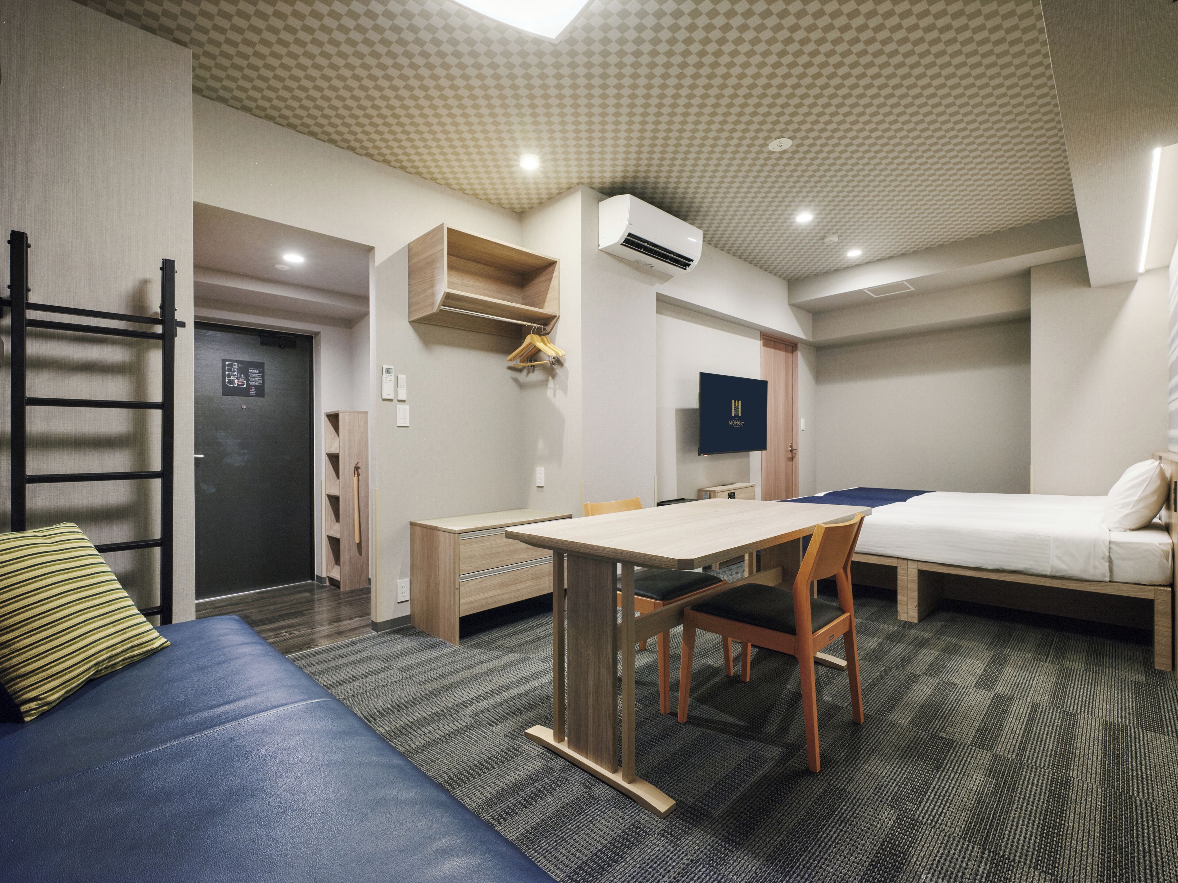 A hotel room with a bed, a desk, a chair, a TV, and a wardrobe.