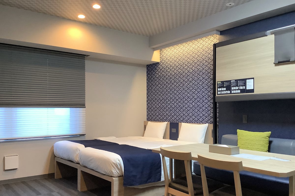 Moderni hotellihuone, jossa on sänky, työpöytä ja tuoli.