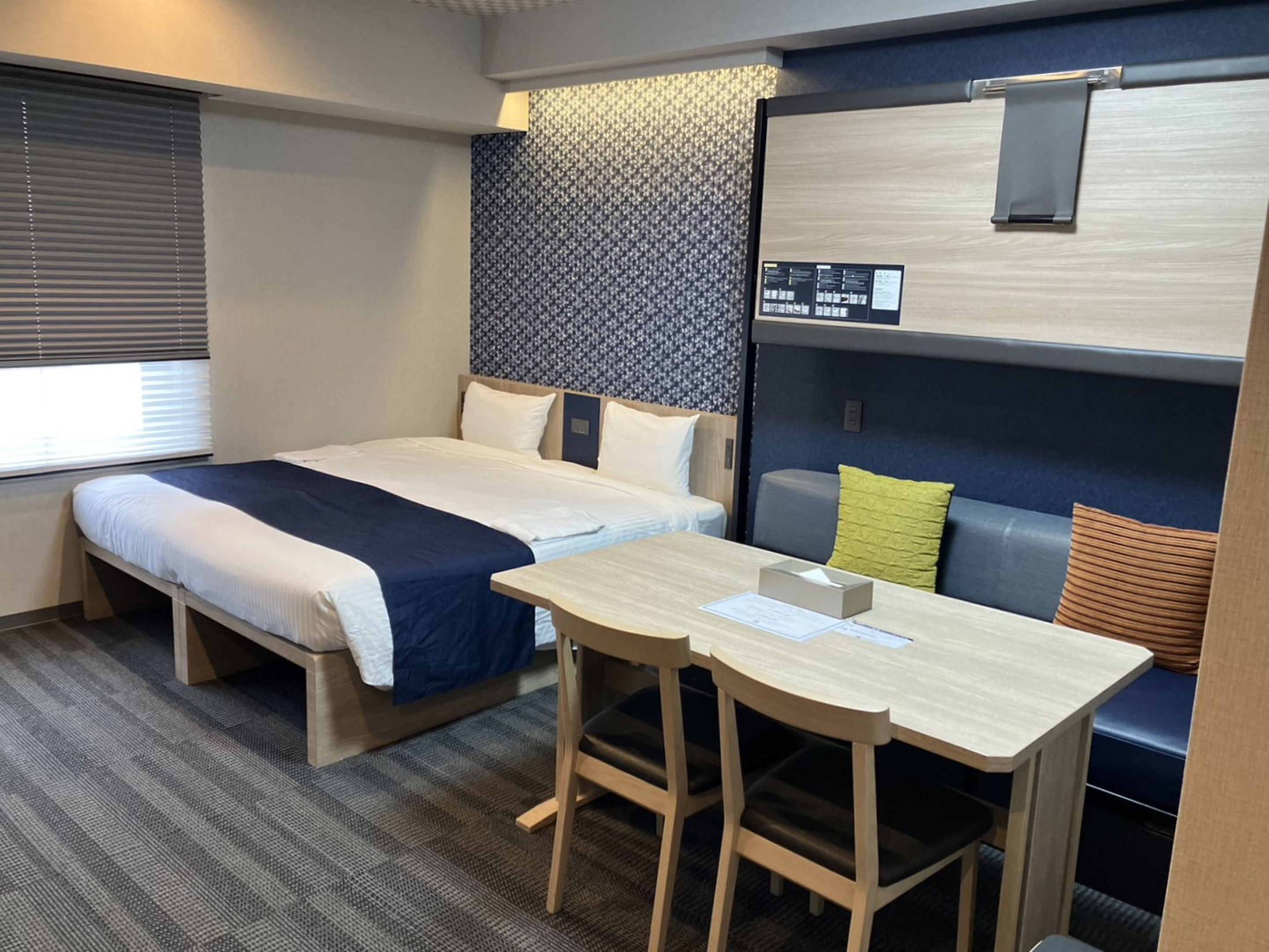 A hotel room with a bed, a desk, and a seating area.