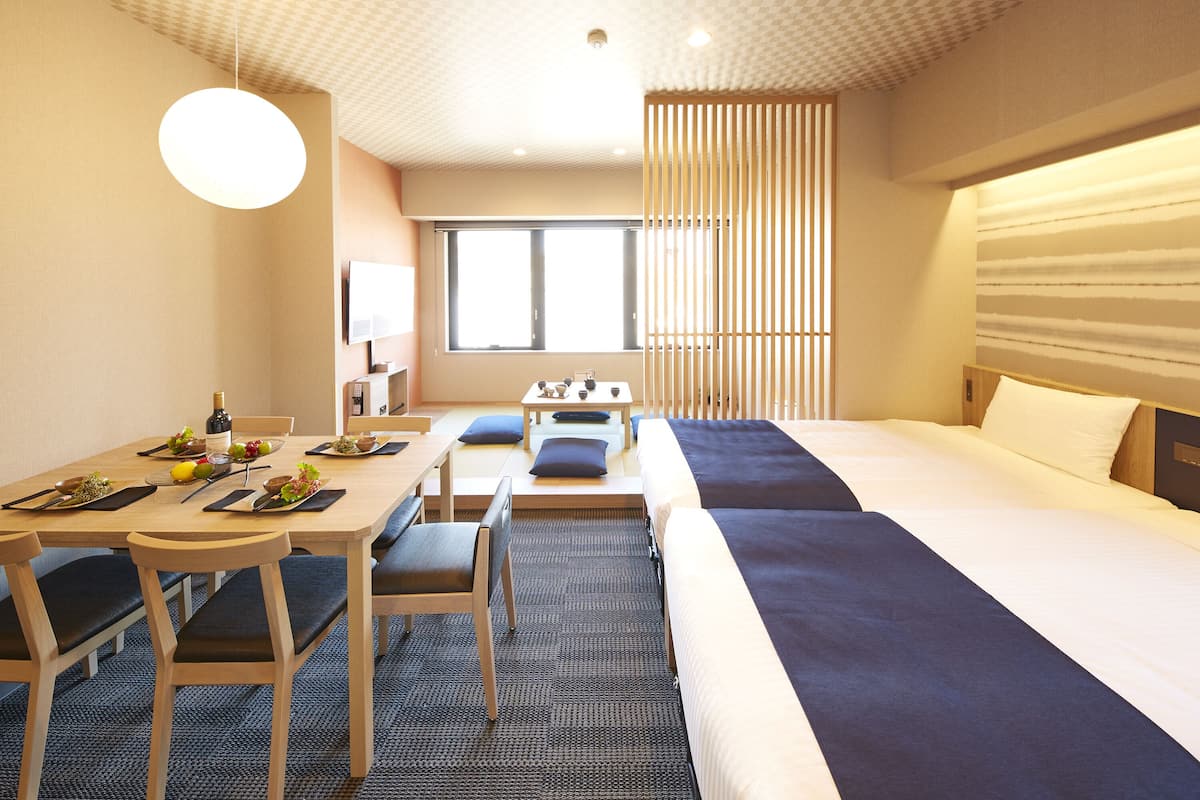 Hotellihuone, jossa on suuri sänky, ruokapöytä tuoleineen ja pieni oleskelualue.