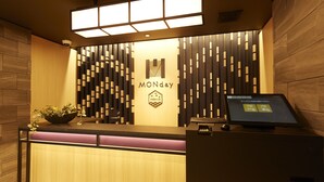 A reception desk with a logo, a computer monitor, and a plant. - MONday Apart Premium GINZA SHINTOMICHO (Tokyo)