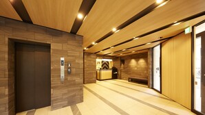 A modern elevator area with wooden paneling and a reception desk. - MONday Apart Premium GINZA SHINTOMICHO (Tokyo)