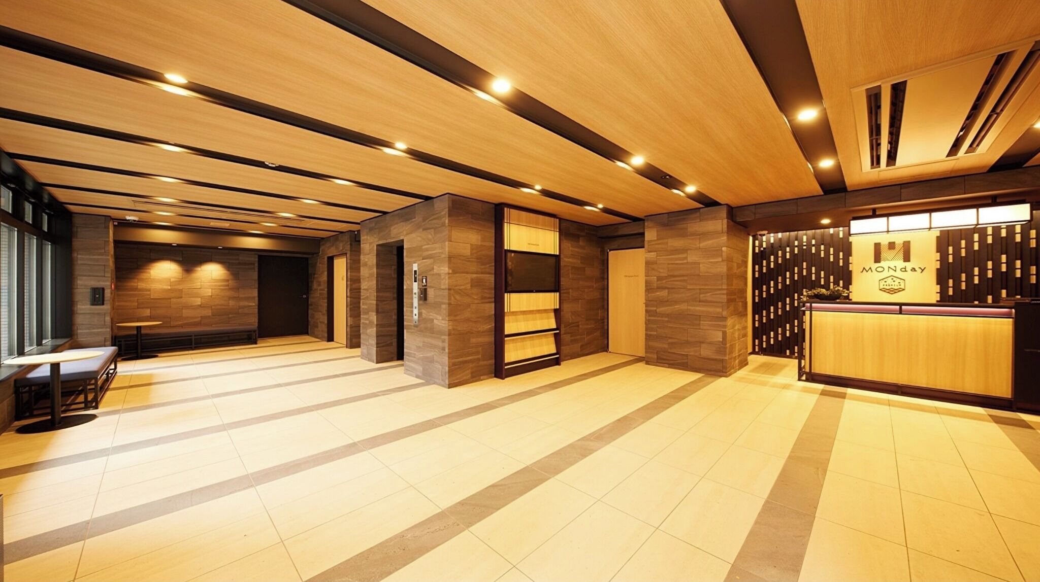 Eine moderne Hotelhalle mit Rezeption, Sitzgelegenheiten und einer Treppe.