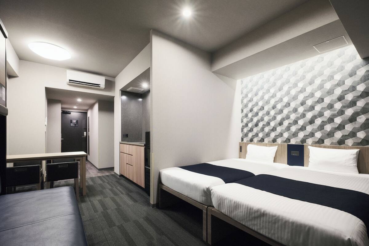 A hotel room with a large bed, a desk, and a kitchenette.