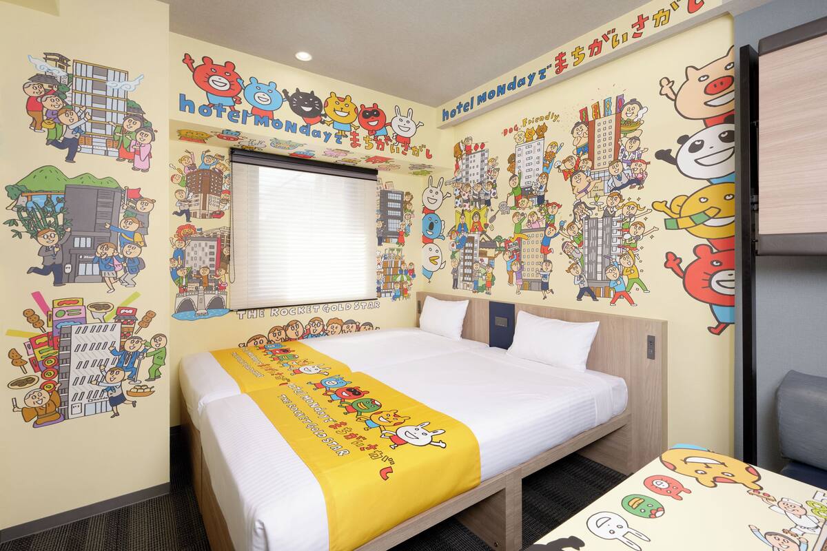 A hotel room with a bed, a window, and walls decorated with cartoon characters.