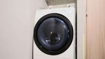 A front-loading washing machine with a control panel and a metal drying rack above it.