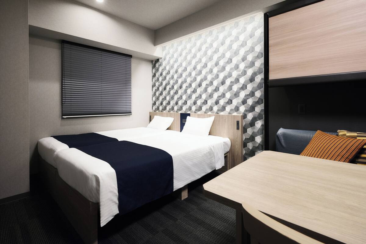 A modern hotel room with a bed, a desk, and a seating area.