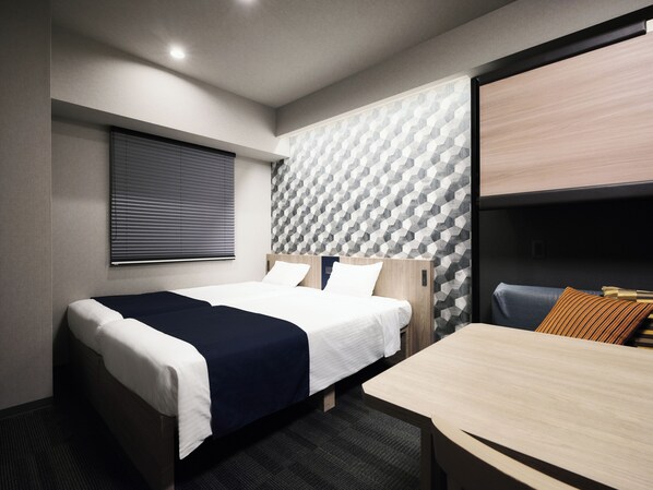 A modern hotel room with a bed, a desk, and a seating area.
