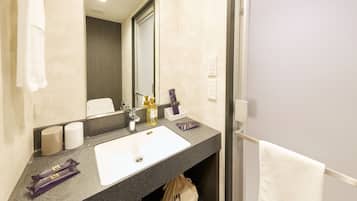 A hotel bathroom with a white sink, dark countertop, and a mirror.