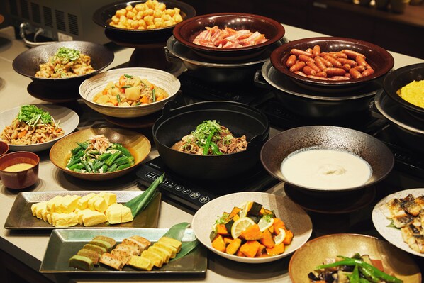 Una variedad de platos en una mesa de buffet, incluyendo carnes, verduras y otros alimentos.