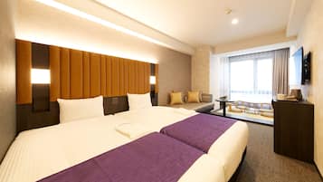 Una habitación de hotel con una cama grande, un sofá, un escritorio y un televisor.
