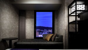A modern hotel room with a large bed, a small round table, and a view of a cityscape through a window. - hotel MONday Kyoto Marutamachi (Kyoto)
