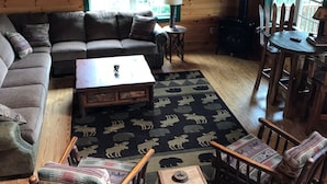 A cozy cabin interior with a wooden floor, a sofa, a coffee table, and two chairs. - Direct Snowmobile and ATV trail from front door (Colebrook)