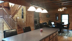 A wooden cabin interior with a dining area, a fireplace, and a staircase. - Direct Snowmobile and ATV trail from front door (Colebrook)