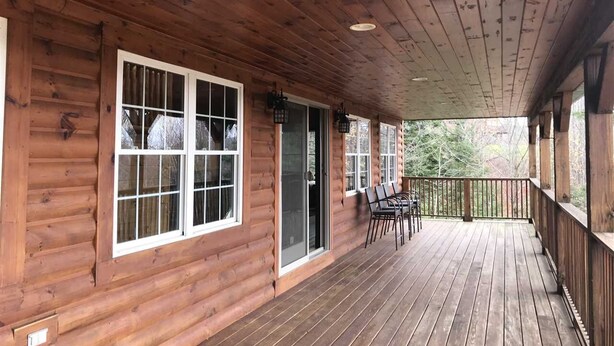 A wooden cabin with a covered porch, large windows, and a sliding glass door. - Direct Snowmobile and ATV trail from front door (Colebrook)