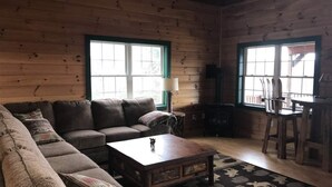 A cozy cabin interior with a sectional sofa, a wooden coffee table, and a fireplace. - Direct Snowmobile and ATV trail from front door (Colebrook)