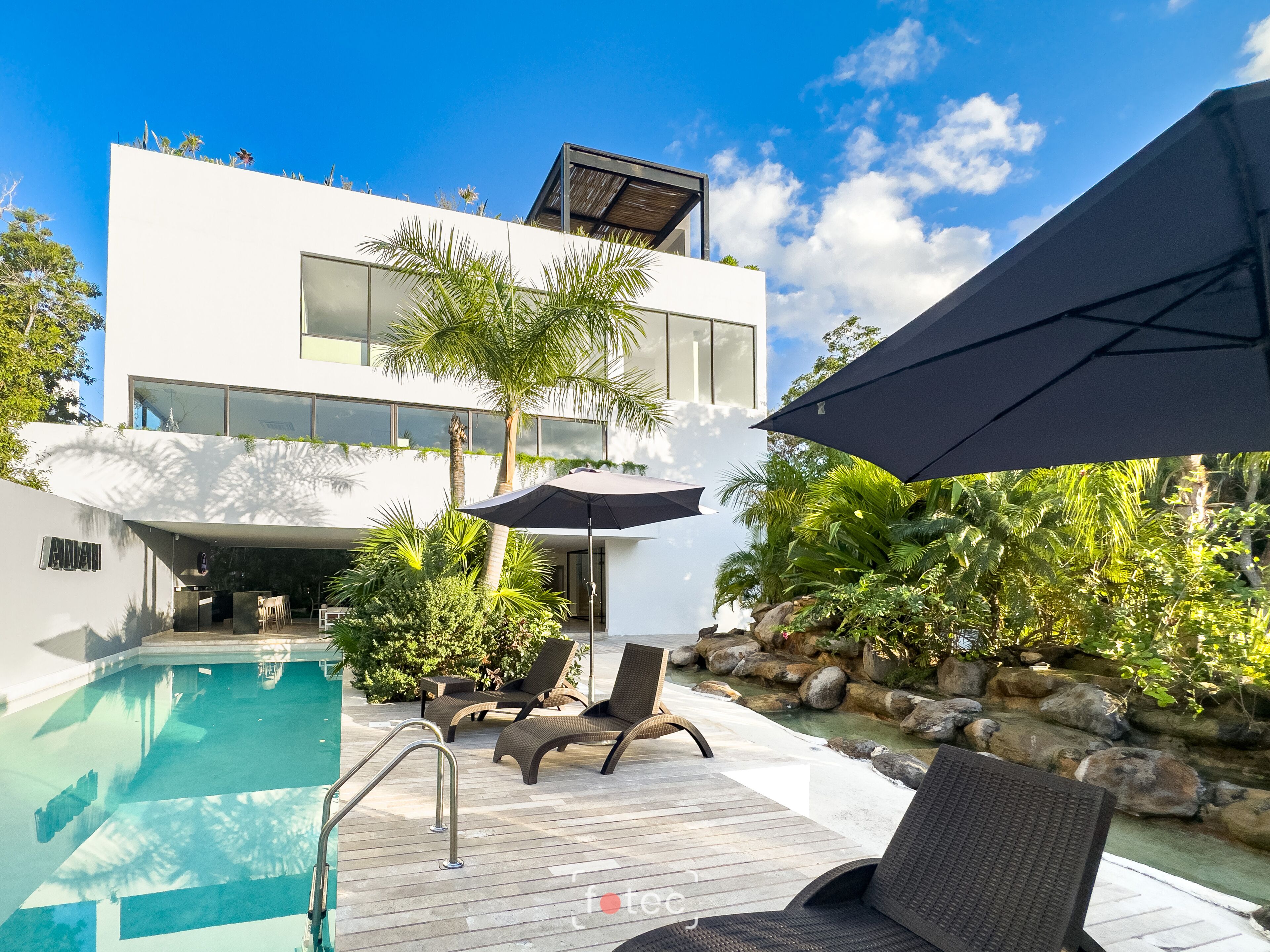Una casa moderna con piscina, mobiliario de exterior y una zona de patio.