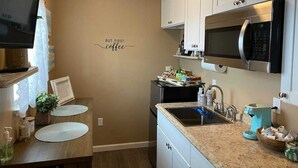 A kitchen with white cabinets, a microwave, a sink, and a coffee maker. - Private country studio, near SMF and UC Davis Campus (Woodland)