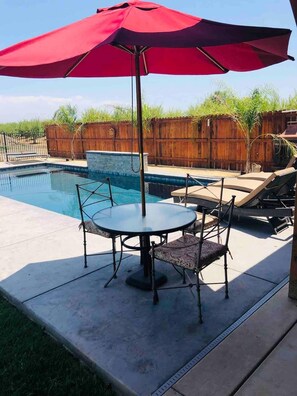 A backyard with a swimming pool, a red umbrella, and outdoor furniture. - Private country studio, near SMF and UC Davis Campus (Woodland)