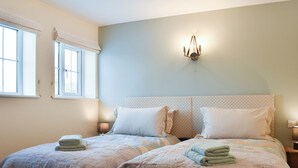 Un dormitorio con dos camas, una ventana y una lámpara fijada a la pared.