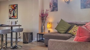 Una sala de estar moderna con un sofá gris, un comedor con mesa y sillas, y un jarrón con flores.