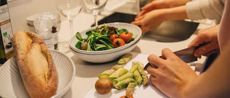 A kitchen counter with a bowl of salad, a loaf of bread, and a cutting board with vegetables.