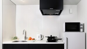 A modern kitchen with a sink, a kettle, a microwave, and a stove. - MIMARU Osaka Shinsaibashi East (Osaka)