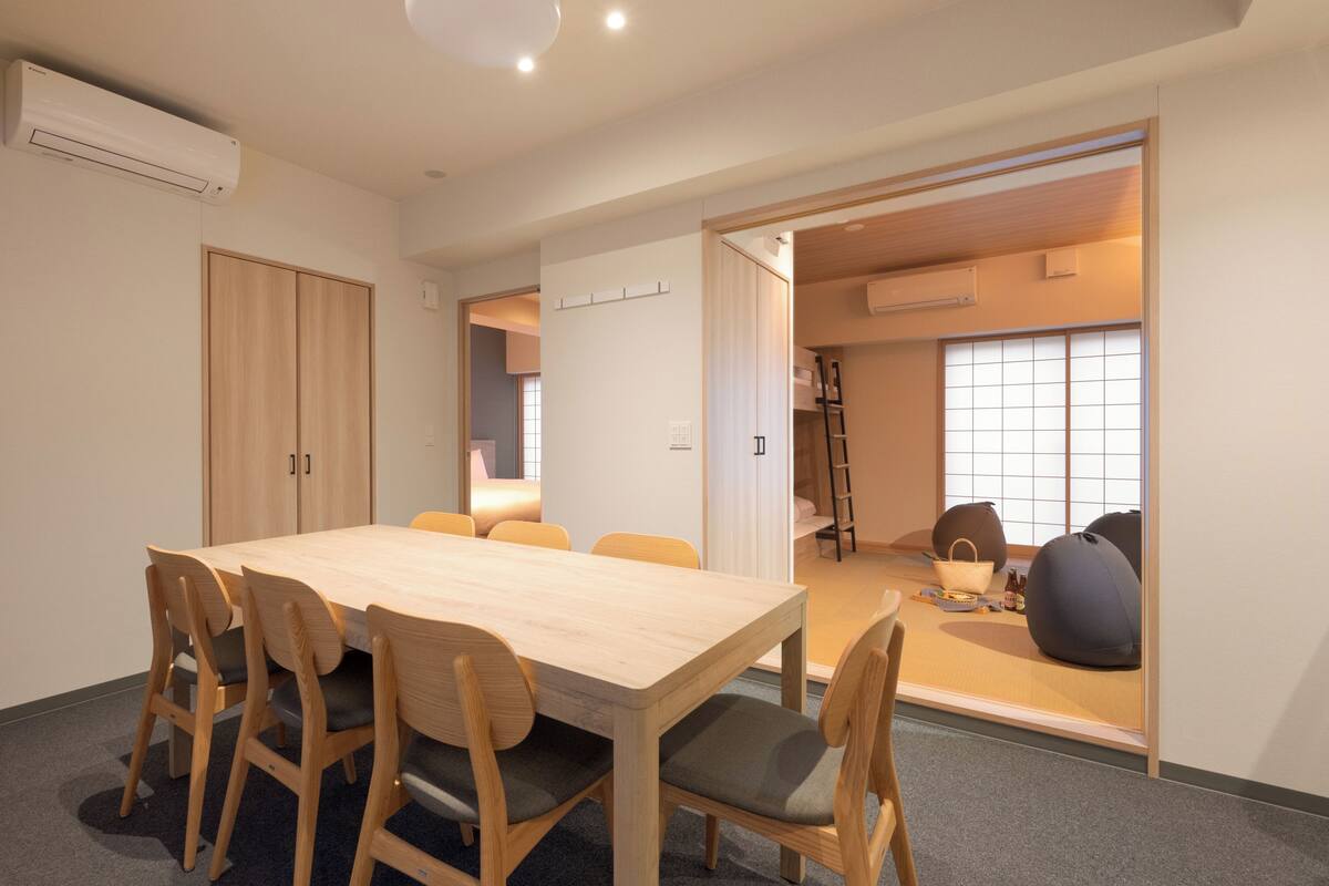 A modern room with a wooden dining table and chairs, a wardrobe, and a sliding door leading to a balcony.