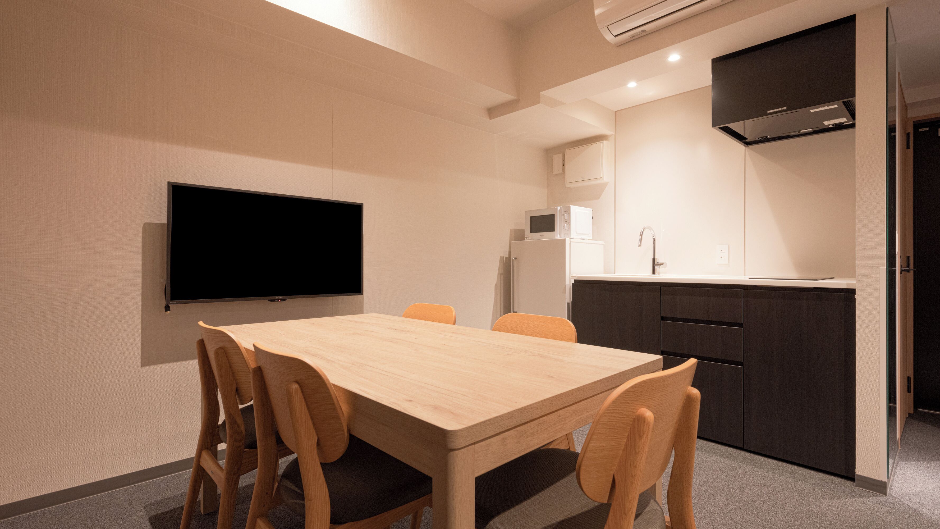 Een moderne keuken met een flatscreen televisie, een houten tafel en stoelen.