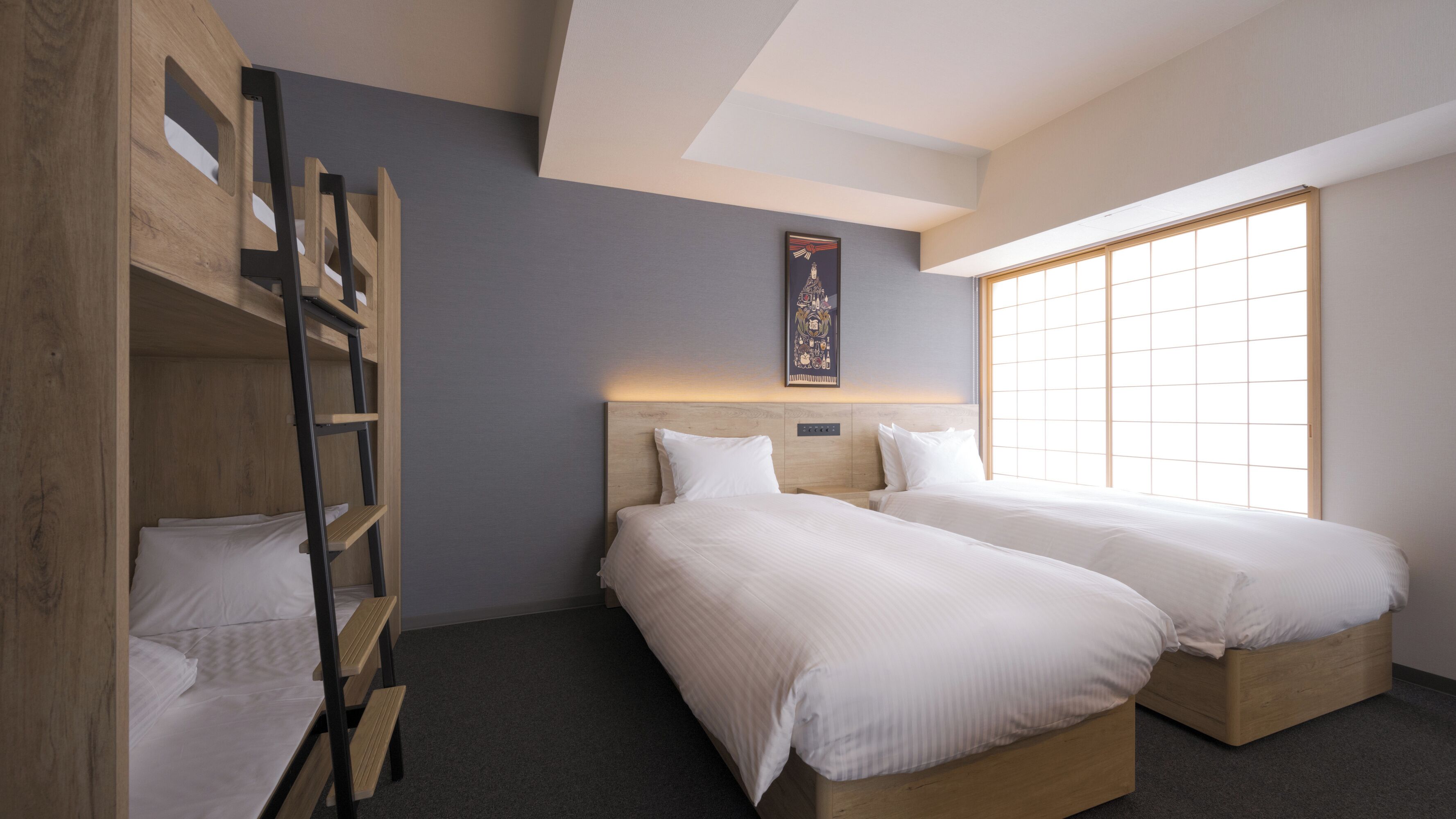 A room with two beds, a bunk bed, a large window, and a wall-mounted artwork.