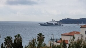 A large yacht docked near a coastal town with buildings and a lighthouse in the background. - Seafront apartment with private parking (La Ciotat)