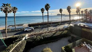 A coastal road with palm trees, a beach, and a clear sky. - Seafront apartment with private parking (La Ciotat)