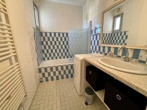 A bathroom with a checkered tile pattern, a white toilet, a sink with a faucet, and a mirror above the sink.