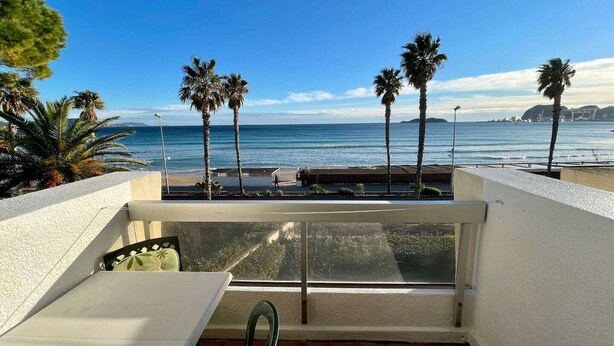 A balcony with a view of the ocean, palm trees, and a clear sky. - Seafront apartment with private parking (La Ciotat)
